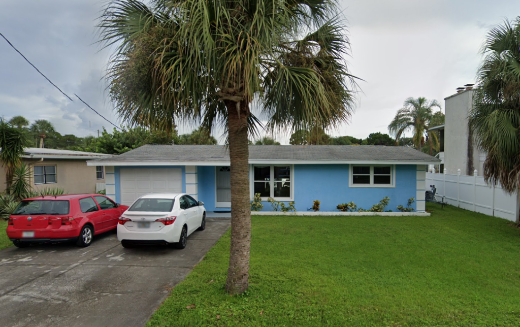 A picture of a one story house, painted blue, with a single car garage